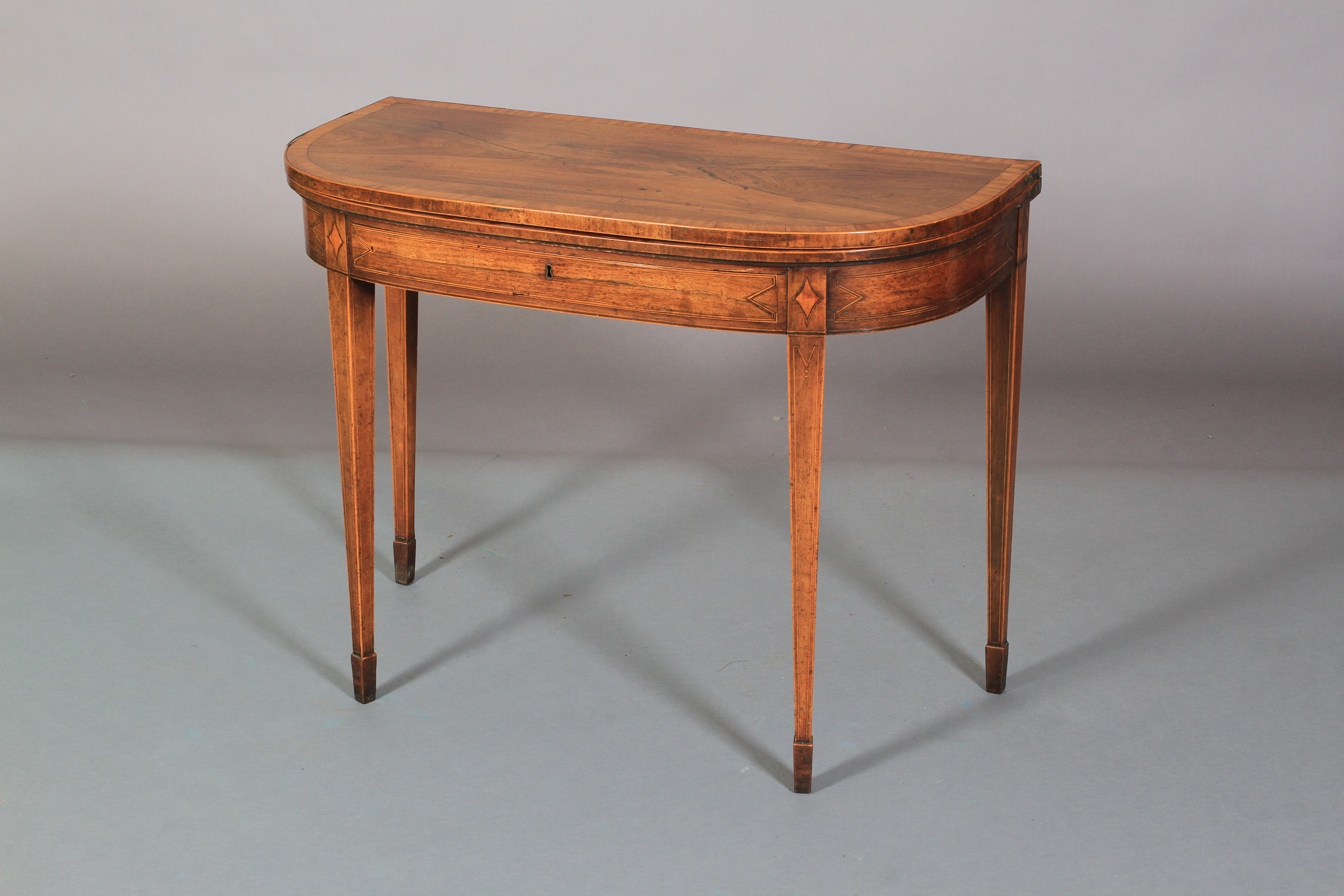 A GEORGE III ROSEWOOD AND SATINWOOD BANDED FOLD-OVER TEA TABLE of 'D' outline, line inlaid with