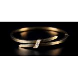 A LATE VICTORIAN STIFF HINGED BANGLE IN 9CT GOLD, the square section crossover front joined by a