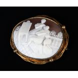 A VICTORIAN SHELL CAMEO BROOCH collet set in gilt base metal, the oval landscape of artist and model