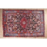AN ANTIQUE PERSIAN HAND MADE BEHBAHAN RUG having an iron red medallion on a black ground filled with