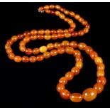 AN EARLY TO MID 20TH CENTURY AMBER NECKLACE of graduated oval beads (approximate maximum size 21mm x