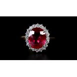 A RUBY AND DIAMOND CLUSTER RING in 18ct gold the oval faceted ruby claw set to the centre and raised