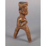 A SOUTH AFRICAN WOOD CARVING of a male figure wearing cap, his hands held together over his chest,