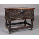 A 17TH CENTURY OAK SMALL BOX or bible box on stand, the two panel later top above a front carved