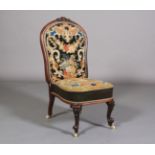 A VICTORIAN ROSEWOOD NURSING CHAIR, having a moulded encircling frame with foliate cresting,