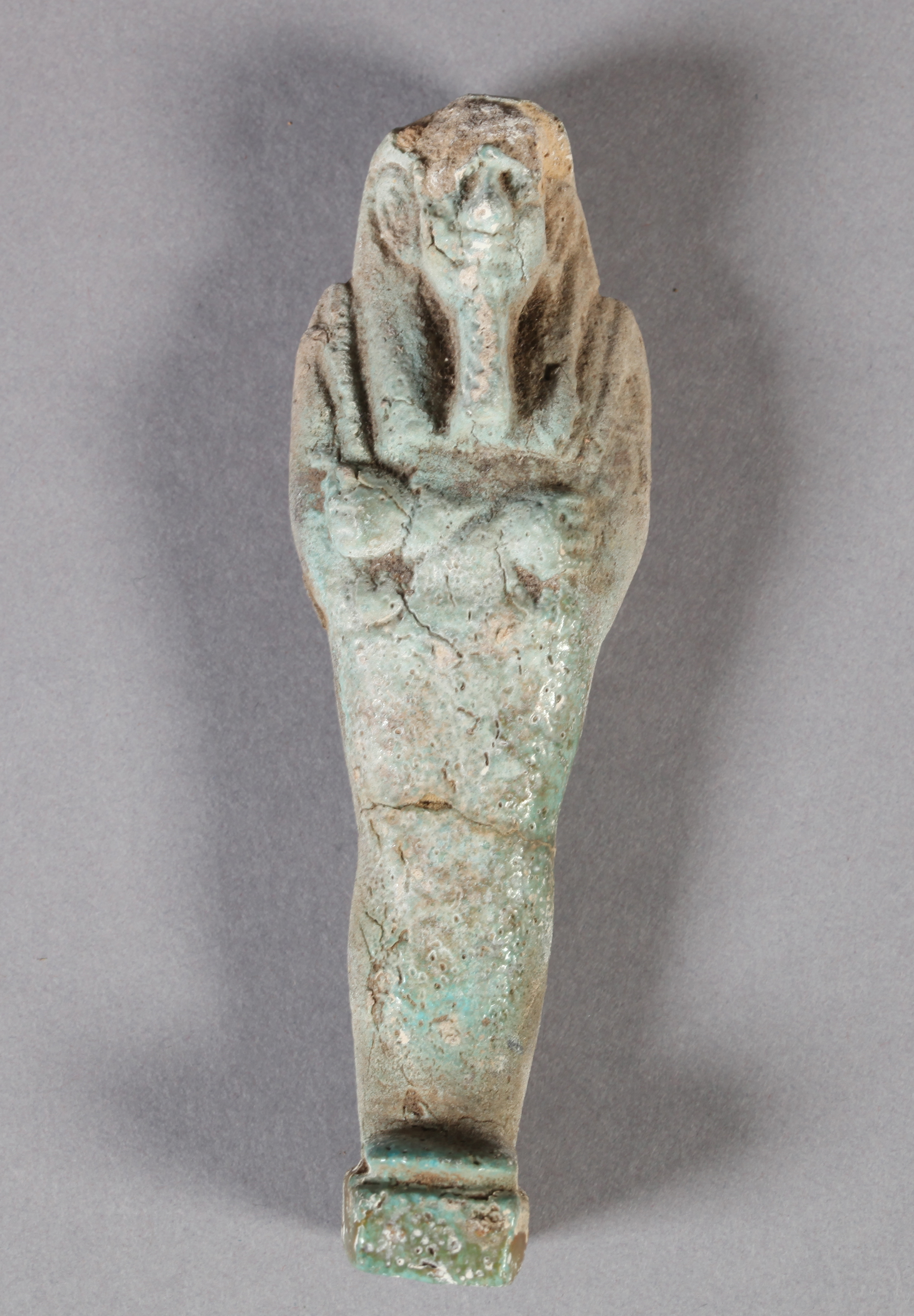 AN EGYPTIAN GLAZED POTTERY USHABTI possibly Osiris with arms crossed, carrying crook and flail,