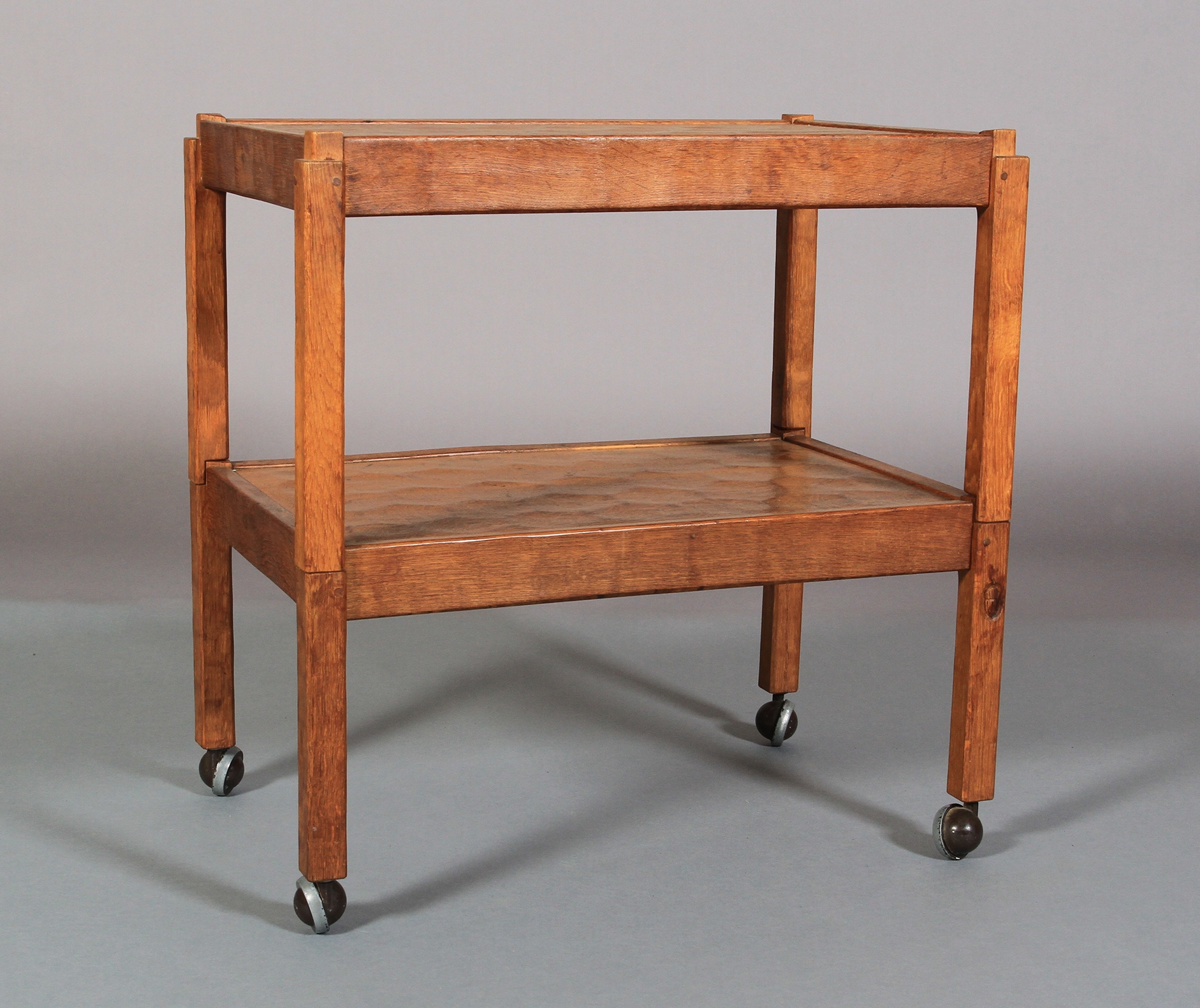 AN ALAN GRAINGER OF BRANDSBY 'ACORN MAN' ENGLISH OAK TWO TIER TROLLEY on square legs and castors,