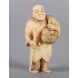 A LATE 19TH CENTURY JAPANESE IVORY NETSUKE, a man carrying a bamboo staff, a basket and package over