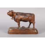 A BLACK FOREST CARVING of a cow wearing neck bell, finely detailed, rustic shaped rectangular base