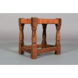 A THOMPSON OF KILBURN 'MOUSEMAN' ENGLISH OAK STOOL with woven leather seat, on octagonal turned
