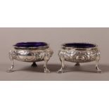 A PAIR OF VICTORIAN SILVER CIRCULAR OPEN SALTS, of floral embossed decoration, on three legs with