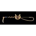 A GEORGE V FOX MASK AND CROP STICK PIN in 14ct gold, set to the eyes with ruby cabochons, with 9ct