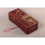 A JAPANESE RED LACQUER BOX AND COVER of rounded rectangular form, the pull off lid decorated in
