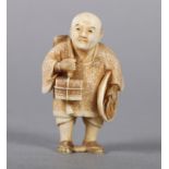 A LATE 19TH CENTURY JAPANESE IVORY NETSUKE, a man standing with his hat under his arm, carrying
