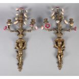 A PAIR OF BRASS AND PORCELAIN THREE LIGHT WALL SCONCES in the form of a cherub holding aloft four
