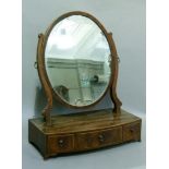 A Regency mahogany toilet mirror, the oval plate supported on a pair of s-scroll uprights, the bow