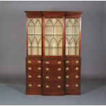 A MAHOGANY BREAKFRONT BOOKCASE, having a moulded and dentil cornice, above three tracery glazed