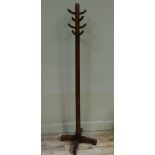 A stained wooden coat rack of tree form with tapered column and quadripartite base, 180cm high