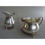 A George V circular sugar basin and cream jug with scroll handles and feet by James Deakin & Sons,