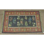 A Kilim style rug decorated with flowers and leafage on the blue grey centre panel, the guard