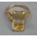 A citrean set dress ring, the step cut stone claw set and raised above bifocated shoulders in yellow