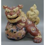A reproduction pottery Dog of Fo, the animal resting on a pierced decorative ball, 26cm wide
