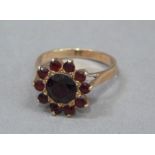 A garnet set cluster dress ring in 9ct rose gold c.1950 claw set within a circular outline,