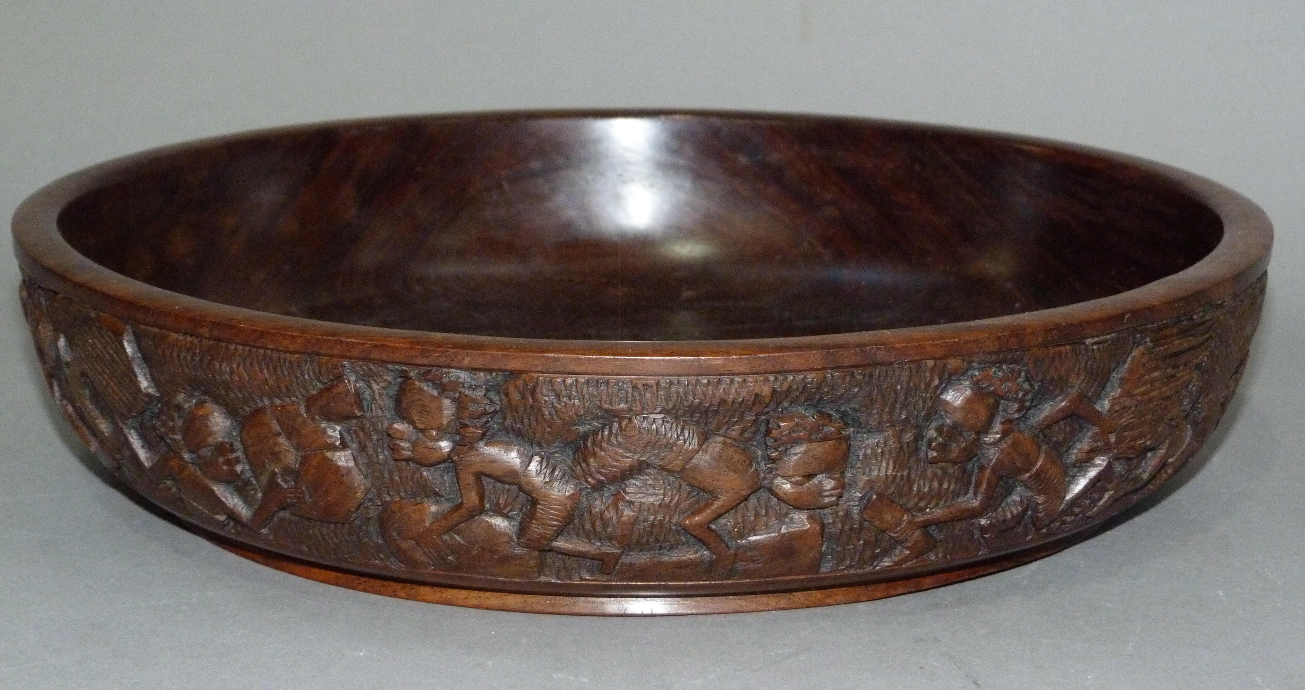 An African hardwood bowl the exterior carved with a continuous scene of figures, 34.5cm