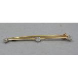 A George V three stone diamond bar brooch in 15ct rose gold, the Old European cut stone claw set