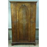 A reproduction figured mahogany wardrobe in Queen Anne style enclosed by a panelled arched figured