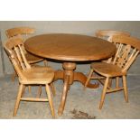 A Victorian style circular pine dining table on turned column and three foliate carved scroll