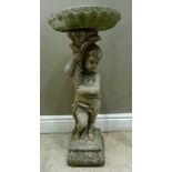A reproduction cast concrete garden figure of a lightly clad cherub holding cornucopia and bowl,