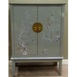 A reproduction Chinese style grey lacquered cupboard, the pair of doors decorated with birds