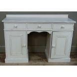 A white painted dressing table with rear upstand the top fitted with three short drawers above a