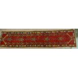 A caucasian multi coloured bordered runner, the red field with stylised temple lamps within a floral