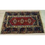 A modern caucasian multi coloured rug, the field with geometric medallions on a madder ground, the