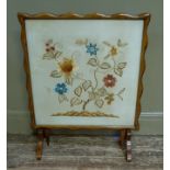 A folding walnut fire screen table, the glazed top crewel work decorated with flowers and foliage,