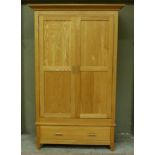 A modern oak wardrobe with flared cavetto cornice enclosed by a pair of panelled doors, long