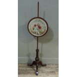 A Victorian mahogany pole screen, the circular banner within a mahogany frame worked in gros and