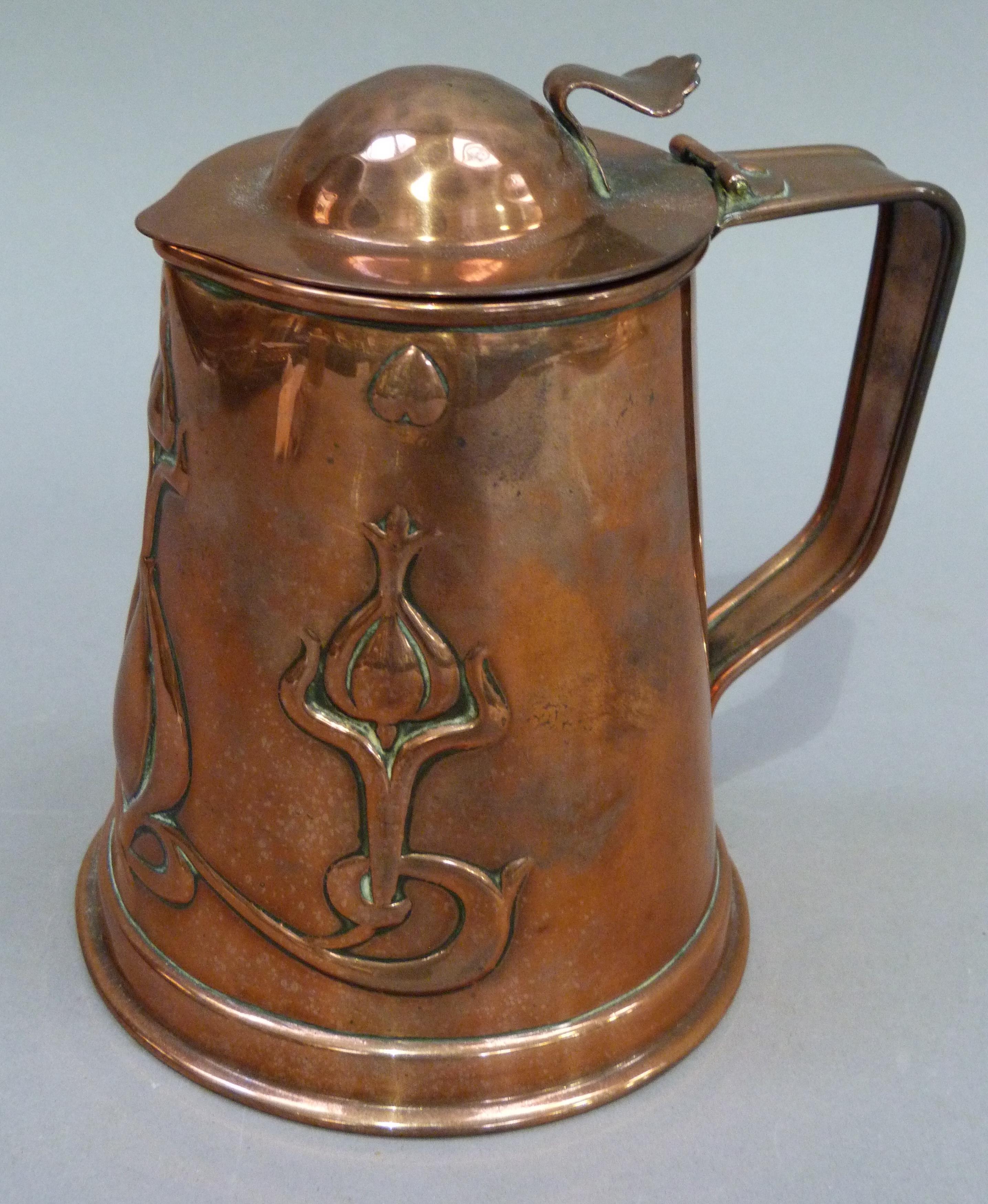 An Art Nouveau copper jug having a domed cover with thumb piece the tapered body embossed with