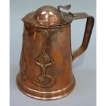 An Art Nouveau copper jug having a domed cover with thumb piece the tapered body embossed with
