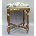 A Louis XVI style giltwood stool the square upholstered top above a foliate carved apron on fluted