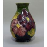A Moorcroft vase, tube lined and painted in mauve and yellow on a green ground with magnolia, 21.5cm