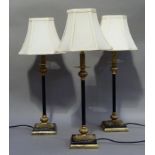 Three black and gilt metal table lamps of classical design on square bases, approximately 45cm to