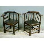 A pair of early 19th century gentleman's corner chairs in oak each having a railed back and turned