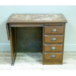 A child's oak desk having a pull slide and four drawers to the right and a drop leaf to the left