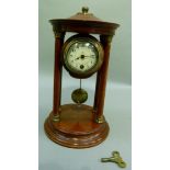 An Edwardian polished beech portico clock, the drum movement having a cream enamelled dial,