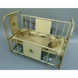 A Lyndylou doll or child's cot, beige painted metal frame with transfer printed panels, 61.5cm wide
