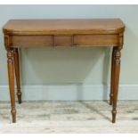 A Victorian mahogany foldover tea table with centre tablet to the frieze and on turned legs