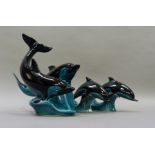A Poole pottery group of two dolphins riding the waves, together with two single dolphins